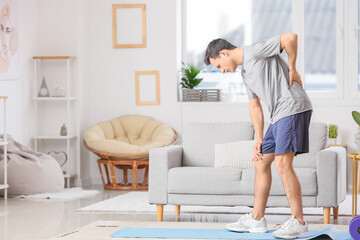 Young man suffering from back pain at home