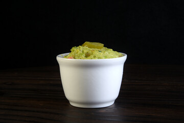 delicious mexican avocado guacamole inside the canister isolated on black background.