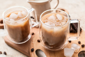 Wooden board with glass cups of tasty iced coffee on table