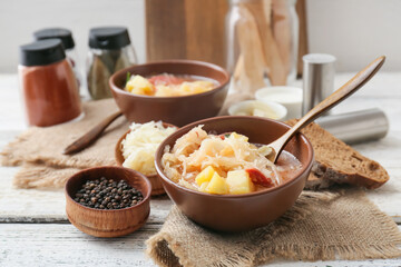 Bowls with tasty sauerkraut soup on table in kitchen