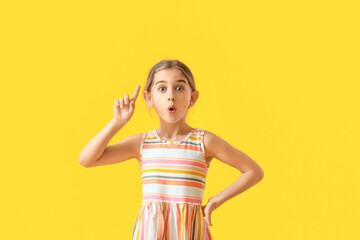 Emotional little girl with raised index finger on color background