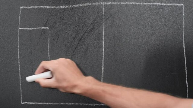 Coach drawing soccer field on blackboard using chalk. Soccer match tactics