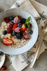 Oatmeal with berries and nuts in a light plate on a table with a tablecloth. Healthy breakfast. Table setting for breakfast.