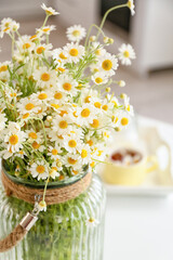 Fototapeta na wymiar Vase with chamomiles on table in kitchen