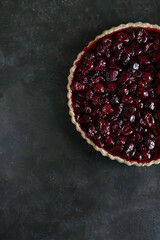 Shortcrust pastry tart with custard and cherry jelly. Pieces of delicious cherry tart on a dark table.