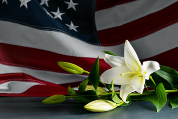 Lily flowers on table against USA flag. National Day of Prayer and Remembrance for the Victims of...