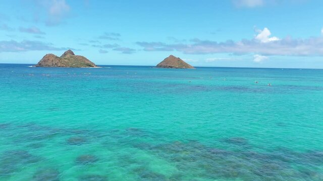 Aerial view of the twin Mokulua Islands off the coast of Lanikai beach in Oahu, Hawaii, with turquoise water and visible coral reefs in the foreground.
