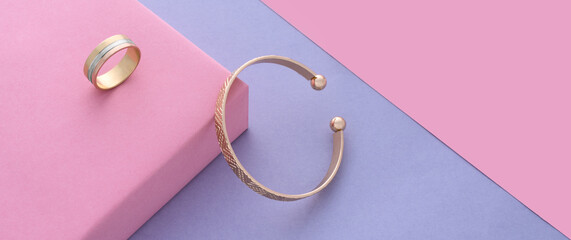 panoramic shot of modern cuff bracelet and ring on pink and purple background with copy space