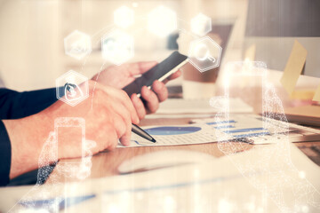 Double exposure of man's hands holding and using a digital device and tech theme hologram drawing. Technology concept.