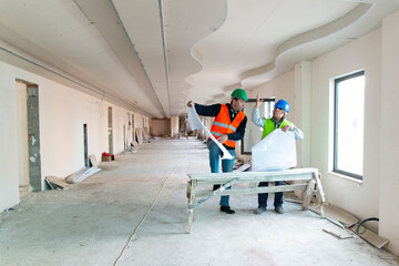 Engineer and construction manager looking at blueprint on site