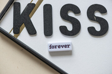 word bead with "forever" and "kiss" in black chalk letters on mixed media background