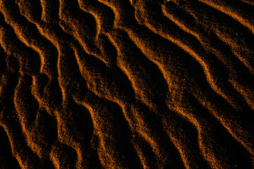 Sand texture outlined by the wind. Wavy shapes of light and shadow.