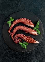 Boiled octopus tentacles on a stone background. Seafood. © александр таланцев