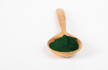 Organic spirulina algae powder in wooden spoon on white background.