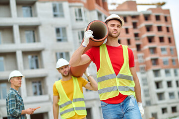 Middle-aged construction manager observing the work of young loaders