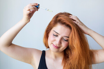 Woman using cosmetics for hair care on white background