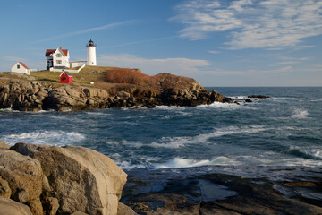 The Nubble Lighthouse on its rocky island in winters late afternoon light and early moonrise