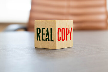 Wooden blocks form the words 'real copy', miniature wooden houses.