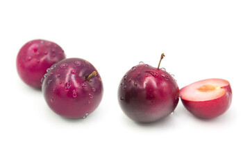 Ripe fresh organic plums whole and half in dew drops isolated on white background.