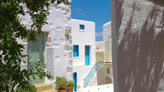 Traditional Greek alleyway with whitewashed houses and the flowerpots on a sunny summer day