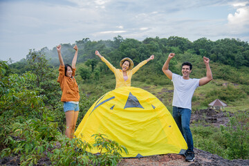 group of male and asian female friends are pitching tents finished among the beautiful mountains...