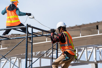 Construction worker wearing safety harness and safety line working on scaffolding at construction site,Working at height.