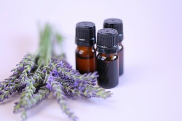 Lavender oil.Three brown glass pharmacy jars with lavender oil and lavender flowers on a lilac...