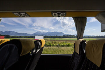 Large window in an empty bus with modern seats with the slovenian mountains of the Julian alps in...