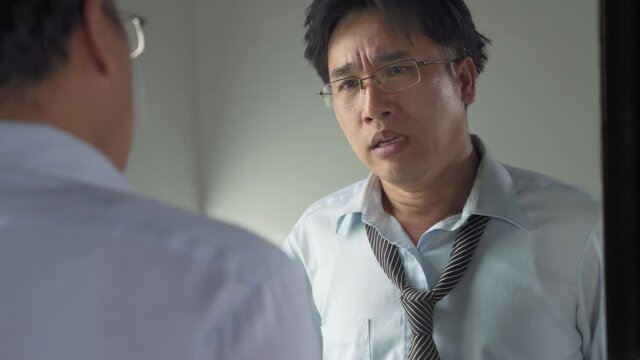 Unemployed Asian man standing in front of mirror screaming and blame himself mistake. Stressed businessman entrepreneur unsuccessful in business. Mental health and economic financial problem concept.