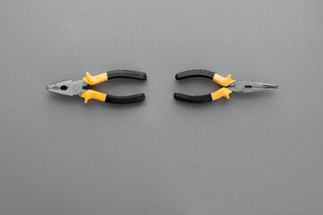 Two pliers of different types on a gray background