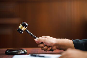 closeup hand Judge with gavel at wooden table indoors at the courtroom - obrazy, fototapety, plakaty