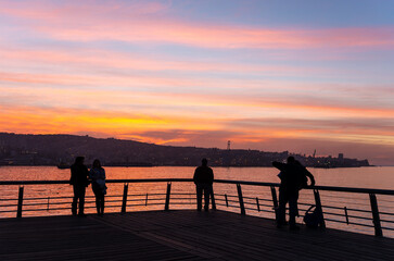 Fototapeta premium Silhouette of people enjoying the sunset on main pier of Valparaiso, Chile.