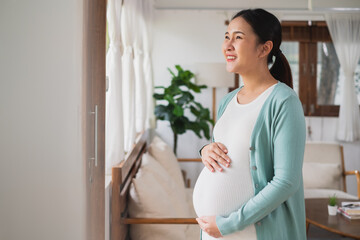 Asian young pregnant woman smile with big belly at home