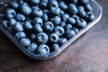 Blueberries in plastic container on rustic background. Selective focus. Shallow depth of field.