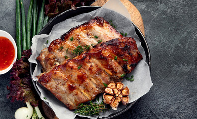 Roasted ribs with snacks and sauce on dark gray background. Gourmet cooking food concept.