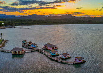 Cottages and docks on the sea during the sunset in Maimon Bay, Puerto Plata, the Dominican Republic - obrazy, fototapety, plakaty