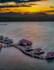 Cottages and docks on the sea during the sunset in Maimon Bay, Puerto Plata - obrazy, fototapety, plakaty