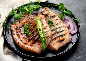 Sliced roasted pork meat on dark gray background. Organic gourmet food concept.
