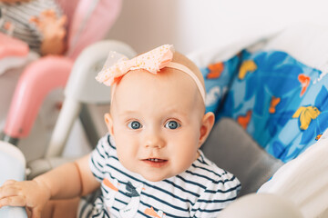 Child in child seat with blue eyes and bow on his head