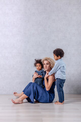 Caucasian young mother with curls hugs African American children. Happy mixed race family adoption