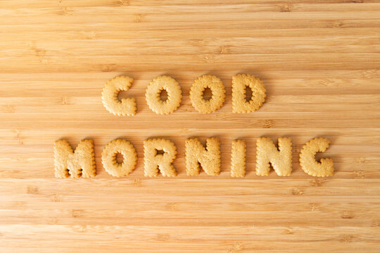 "Good Morning" inscription letters phrase made from cookies or biscuits on the sunny light wooden background from above, top view, flat lay,copy paste. Energetic beginning of the early day concept.