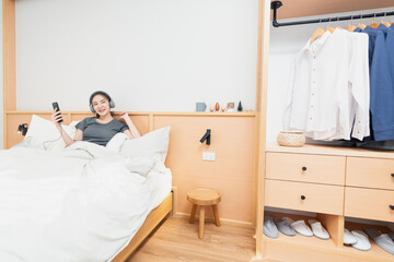 Bedroom concept on the comfortable bed a girl listening her favorite songs by wearing a headphone in the morning