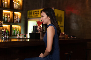Nightlife concept a gorgeous girl in a blue collared dress looking confident sitting beside the bar...
