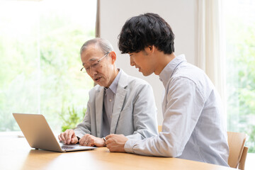 パソコンを見る若い男性とシニア