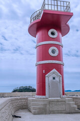 Red lighthouse on concrete pier located in Mongsan harbor in Taean, South Korea.