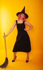 Portrait of her she nice-looking attractive pretty charming lovely slender cheerful cheery lady wizard holding in hand broom festal event isolated bright vivid shine vibrant yellow color background