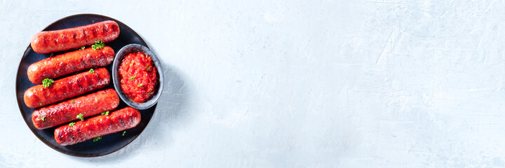 Sausages panorama with a place for text. Grilled sausages, shot from the top with ketchup and...