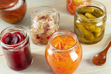 Probiotic foods. Fermented food. Canned sour cabbage, carrot, pickles and other preserves in glass jars. Homemade vegan cooking on a rustic wooden background