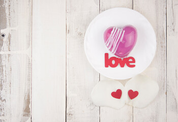 word love and white petals rose with red cake in the shape of a heart is on the table. Romantic date.
