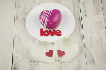 word love and white petals rose with red cake in the shape of a heart is on the table. Romantic date.